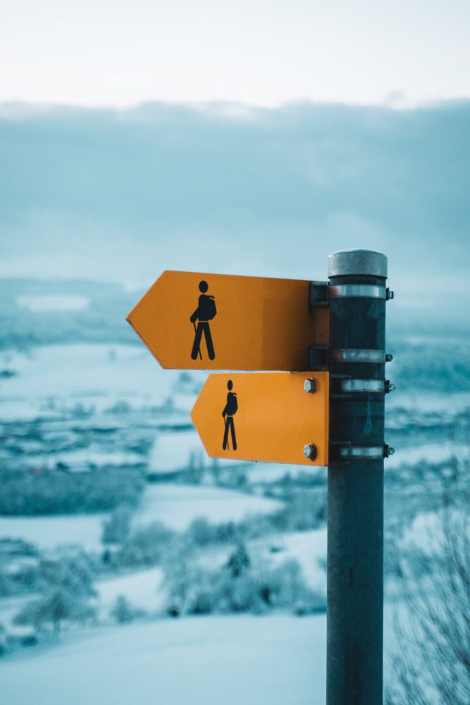 Wegweiser vor verschneiter Landschaft